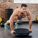 Muscular man doing bosu push ups at the gym