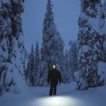 Woman walking with a headlamp in a snowy Riisitunturi National P